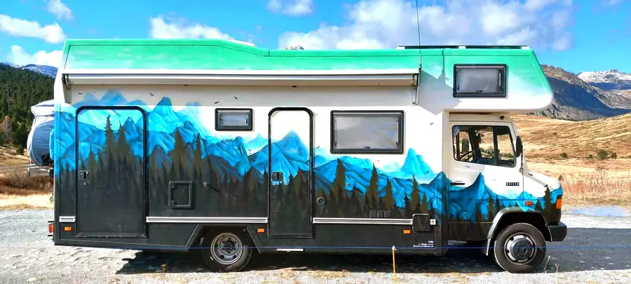 Camping-car entièrement peint d'une forêt de sapins et de montagnes bleues